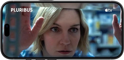 iPhone 18 Pro, landscape mode, displaying a close-up of a woman looking through a shelf. Series title: Pluribus